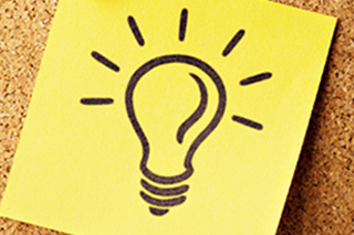 Yellow sticky note with a lightbulb idea drawing pinned to a cork board.