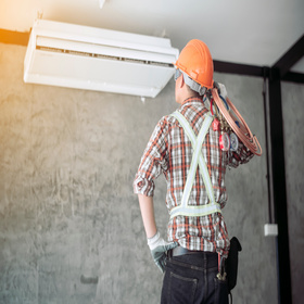 Air technician wearing safety equipment checking the quality of the newly installed air conditioner.