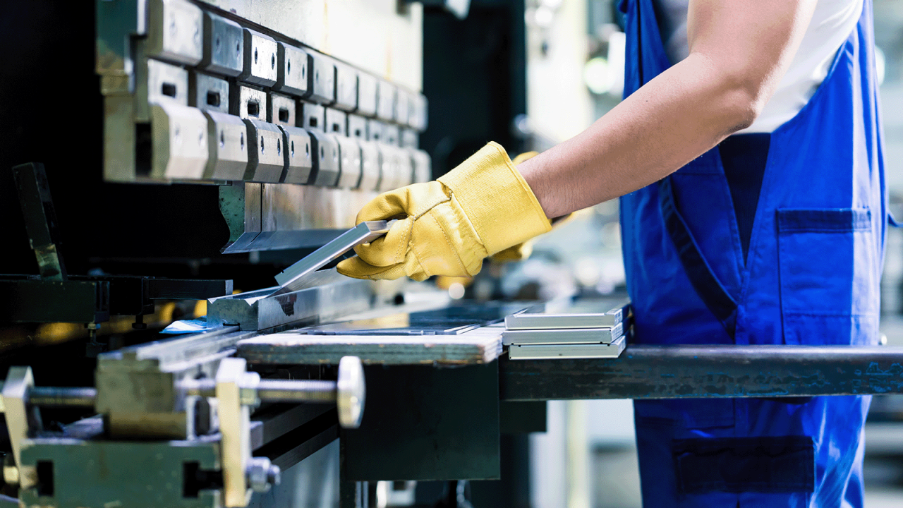 Ein Industriearbeiter inspiziert ein Werkstück auf dem Boden der Werkshalle.