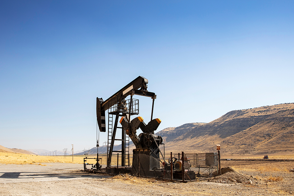 Derrick pétrolier dans un champ pétrolifère désertique.