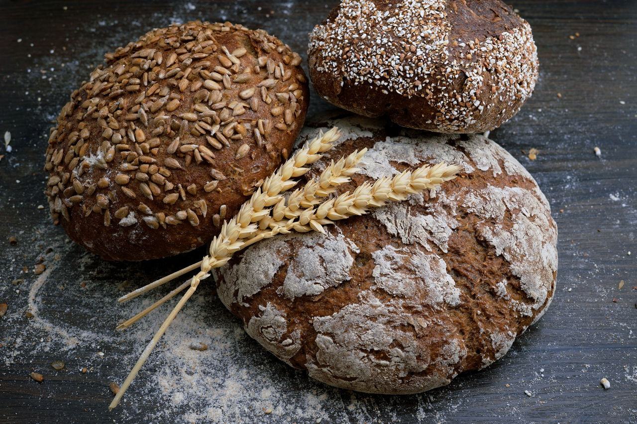 Trois pains ronds avec des graines et des morceaux de blé sur le dessus.
