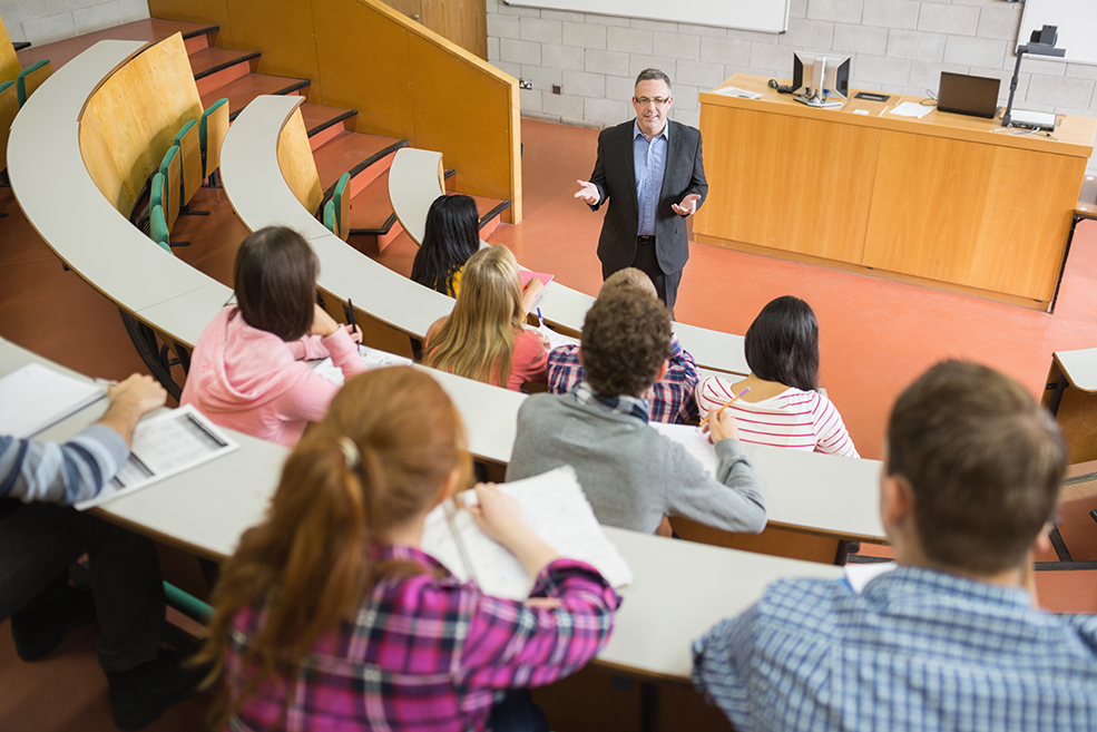 Professor ensinando estatística para uma aula cheia de alunos de graduação.